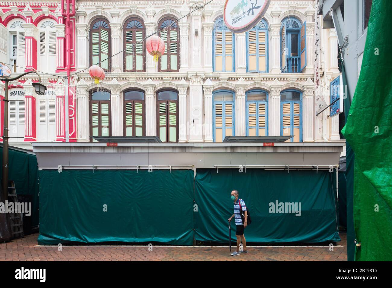 An old man wear surgical mask strolled through the empty of Chinatown streets, all retails and small business are closed. Singapore. Stock Photo