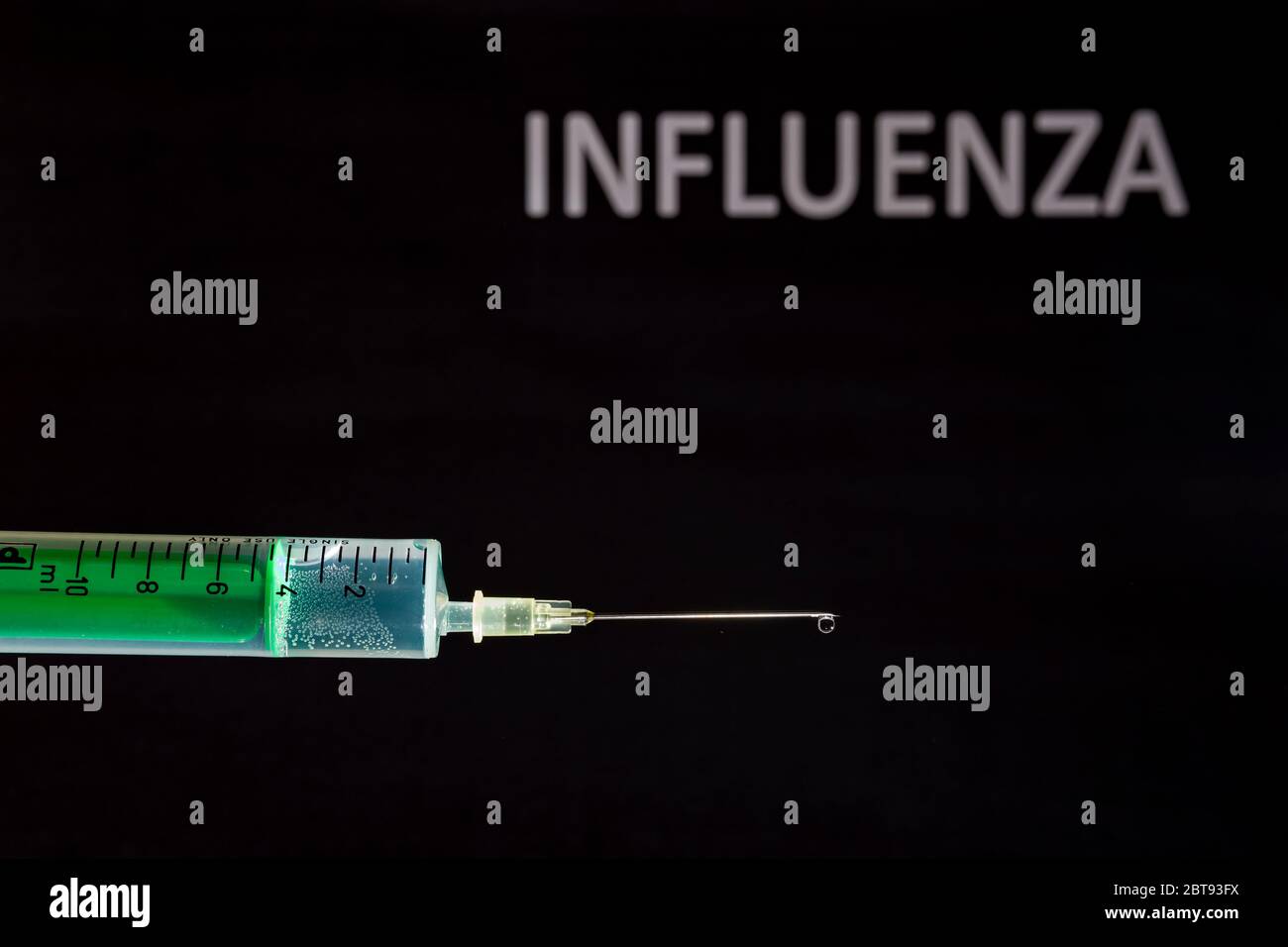 This photo illustration shows a disposable syringe with hypodermic needle, INFLUENZA written on a black board behind Stock Photo