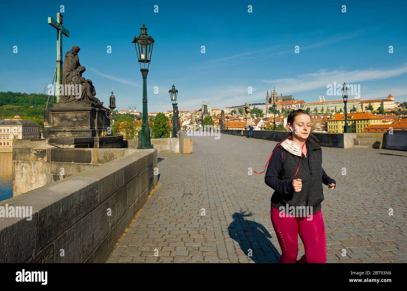 Prague, Czech Republic. Young woman running on famous Charles Bridge with  face mask on neck. Prague Castle and Lesser Town on background. May 2020  Stock Photo - Alamy