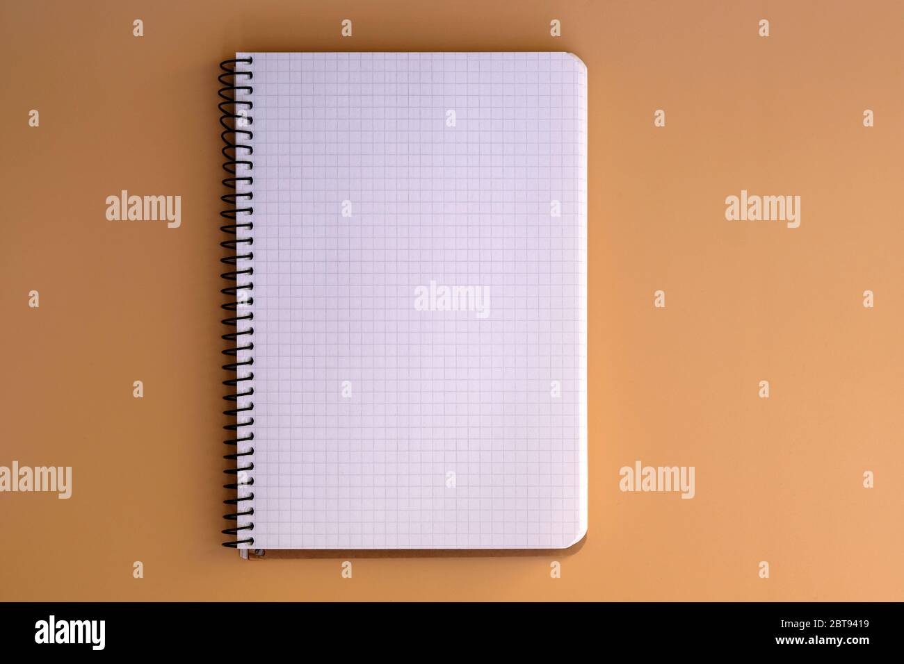 Notebook with spring and sheets in a cage top view. Blank paper in a notebook on a beige background. Stationery, notebook for notes. Copy space. Stock Photo