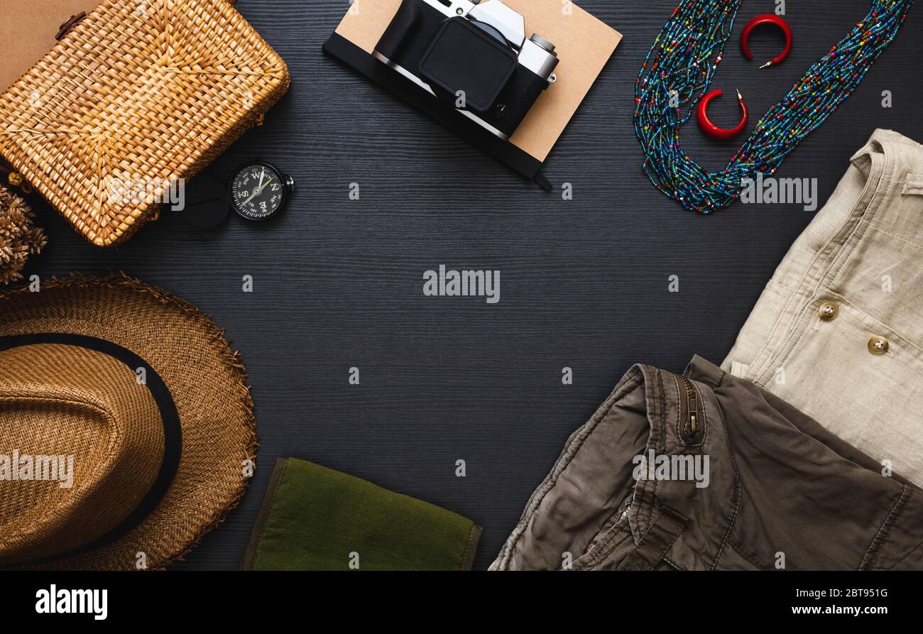 summer travel flat lay of traveller accessories set.cloth,hat,yellow wicker bag,camera and notebook on black wooden table with copy space Stock Photo