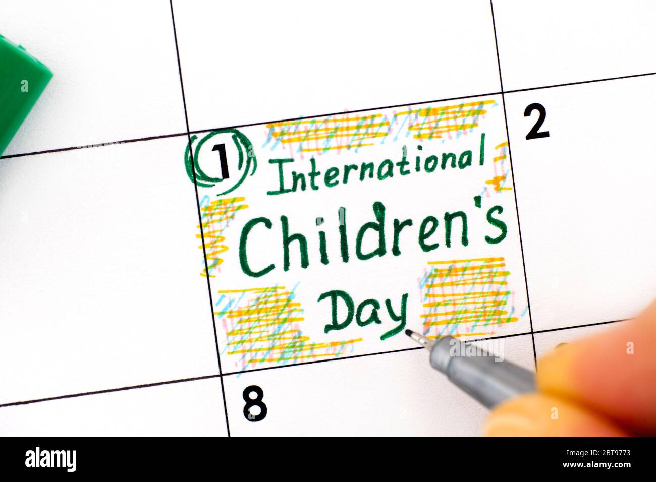 Woman fingers with pen writing reminder International Children's Day in calendar. June 01. Stock Photo