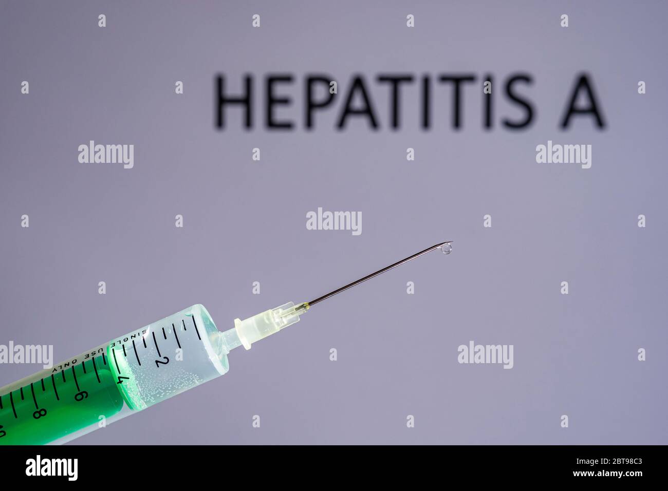 This photo illustration shows a disposable syringe with hypodermic needle, HEPATITIS A written on a grey board behind Stock Photo