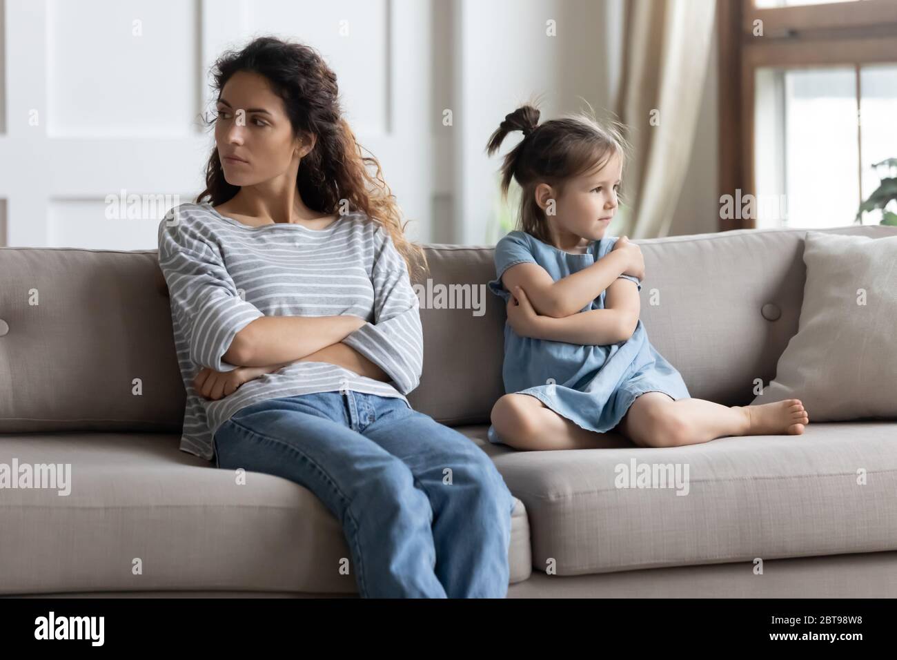 Angry mother and little daughter ignoring each other after quarrel Stock Photo