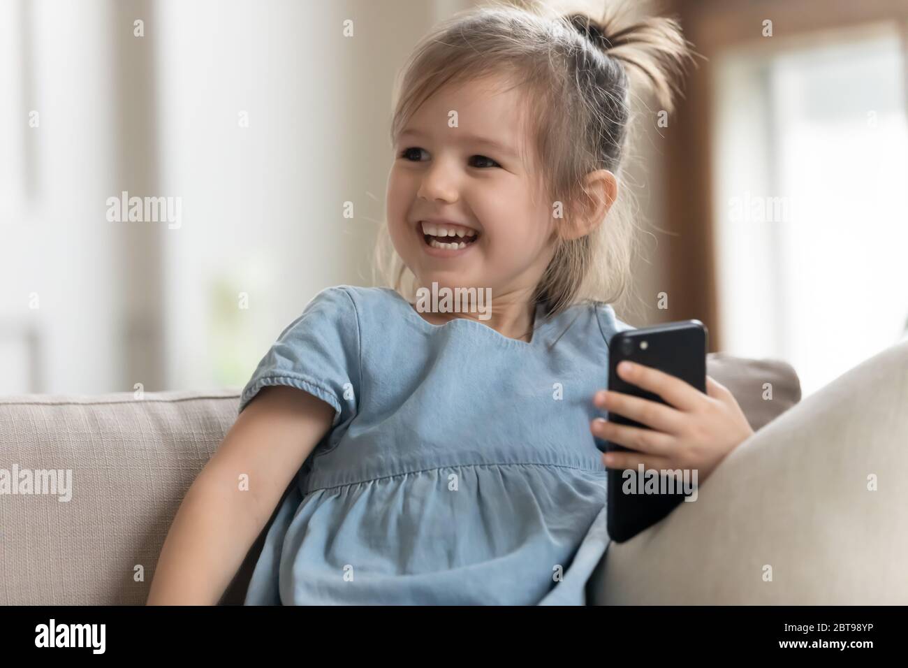 Close up smiling funny little girl holding phone, having fun Stock Photo