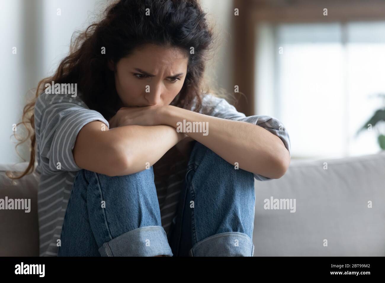 Close up depressed young woman sitting alone, thinking about problems Stock Photo