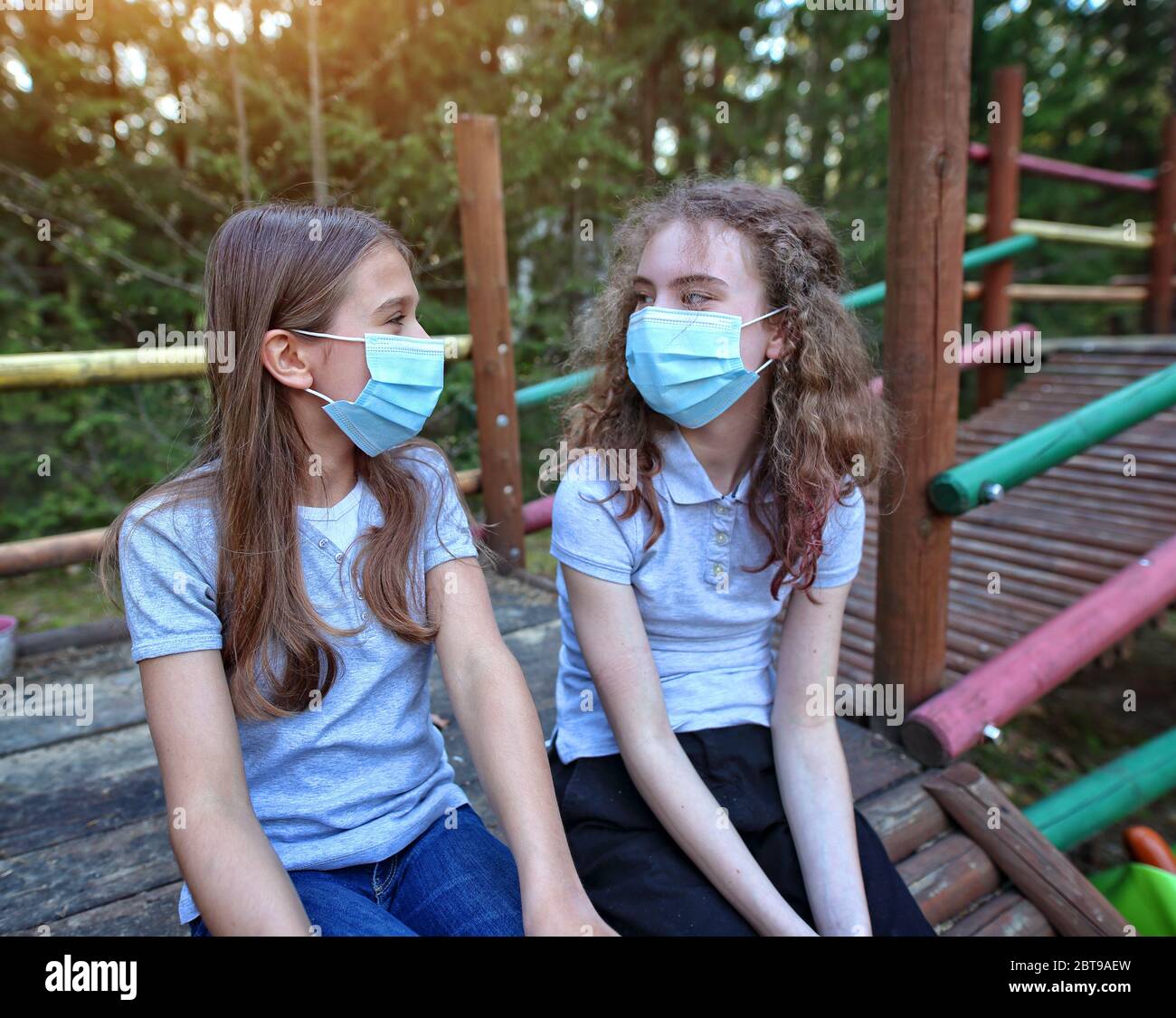Young girl friends laugh and talk during the coronavirus plague outside Stock Photo
