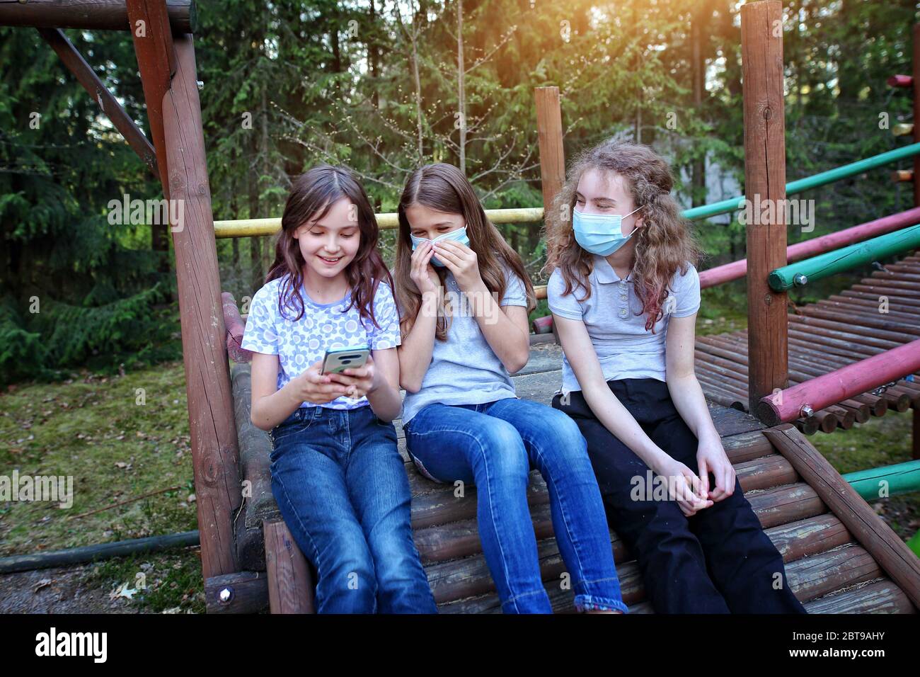 Young girl friends laugh and talk during the coronavirus plague outside Stock Photo