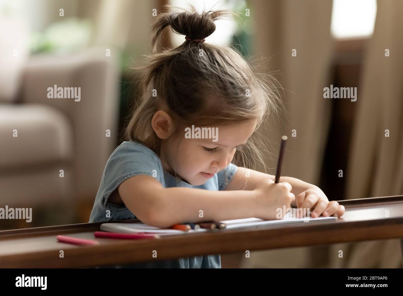 Close up cute little girl drawing with colorful pencils Stock Photo