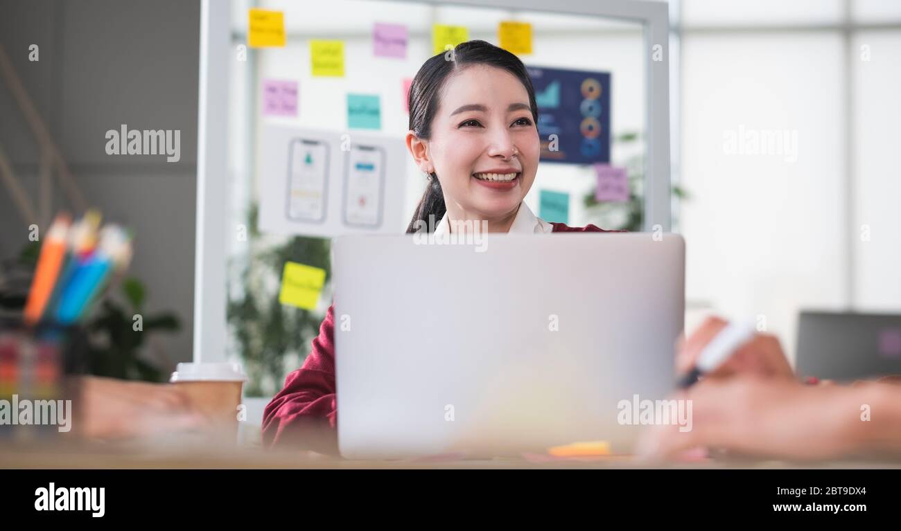 portrait of asian female leader smiling when meeting with ux developer and ui designer about mobile app interface wireframe design on meeting table at Stock Photo