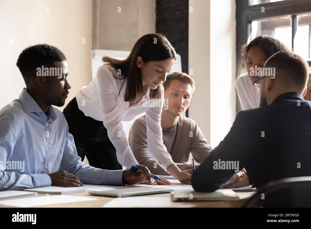 Diverse colleagues working on project together, sitting at table Stock Photo