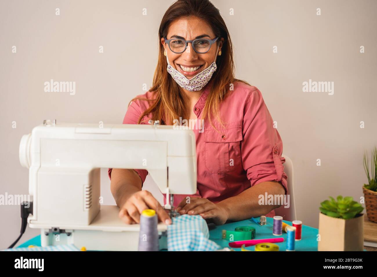 Woman worker using sewing machine while making face medical masks during coronavirus outbreak - Home made diy protective mask against virus Stock Photo
