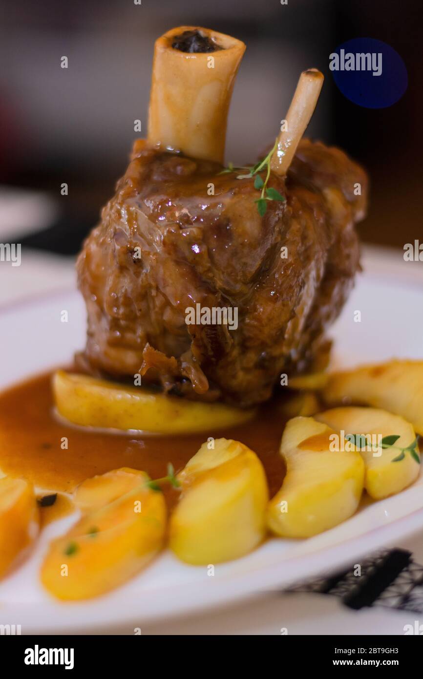 Baked pork knuckle recipe with golden apple slices, thyme, vegetables