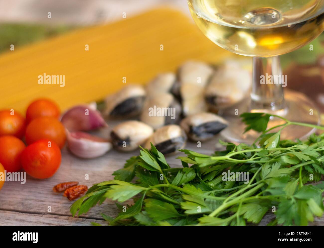 Ingredients for spaghetti alle vongole, an italian traditional recipe: spaghettis, clams, tomatoes, garlic, chilli, parsley and white wine Stock Photo