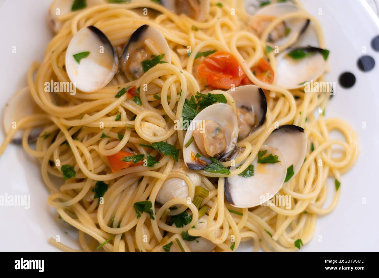 Spaghetti alle vongole, an italian traditional recipe with spaghettis, clams, tomatoes, garlic, chilli, parsley and white wine Stock Photo