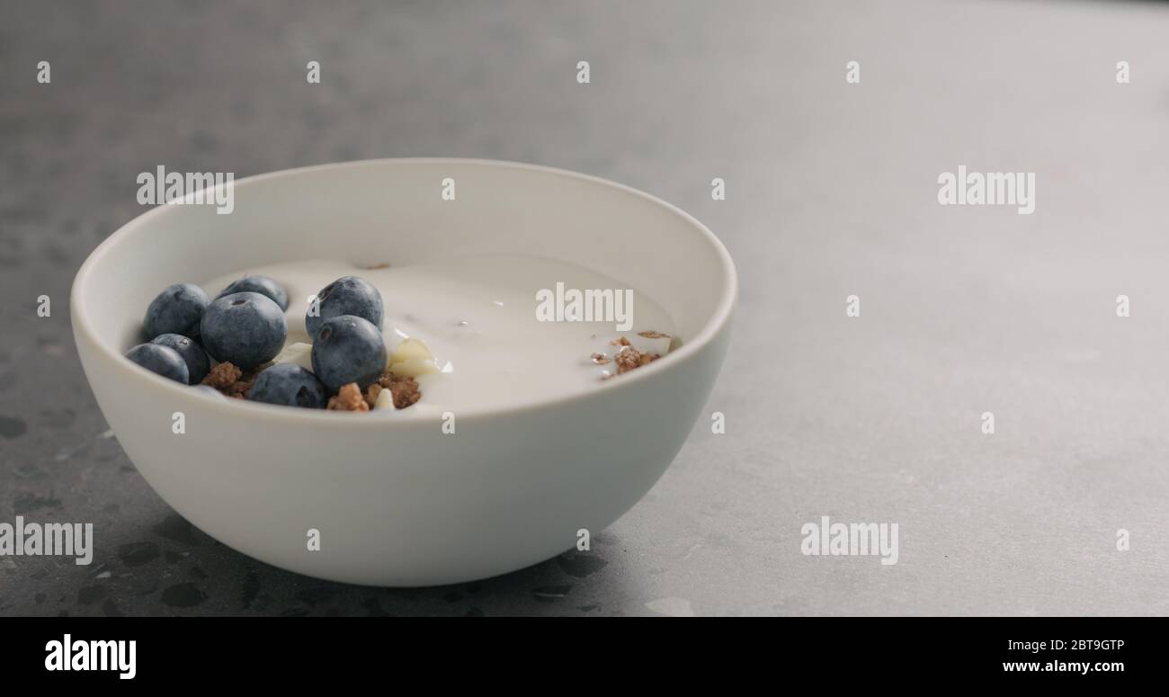 ripe blueberries and chocolate granola in white bowl on terrazzo surface Stock Photo