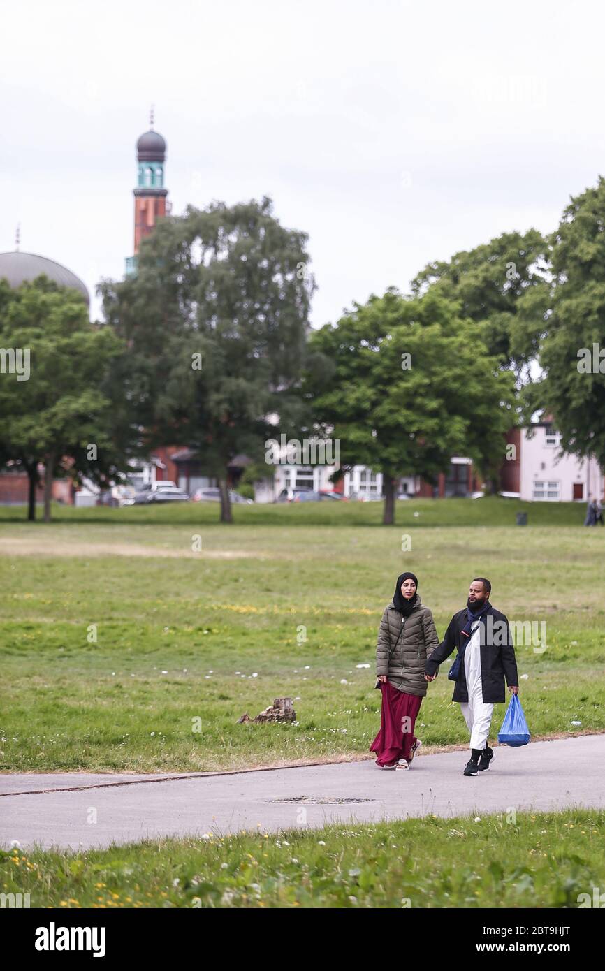 A young moslem or muslim married couple walk in the park, Small Heath, Birmingham UK with a mosque in the background Stock Photo