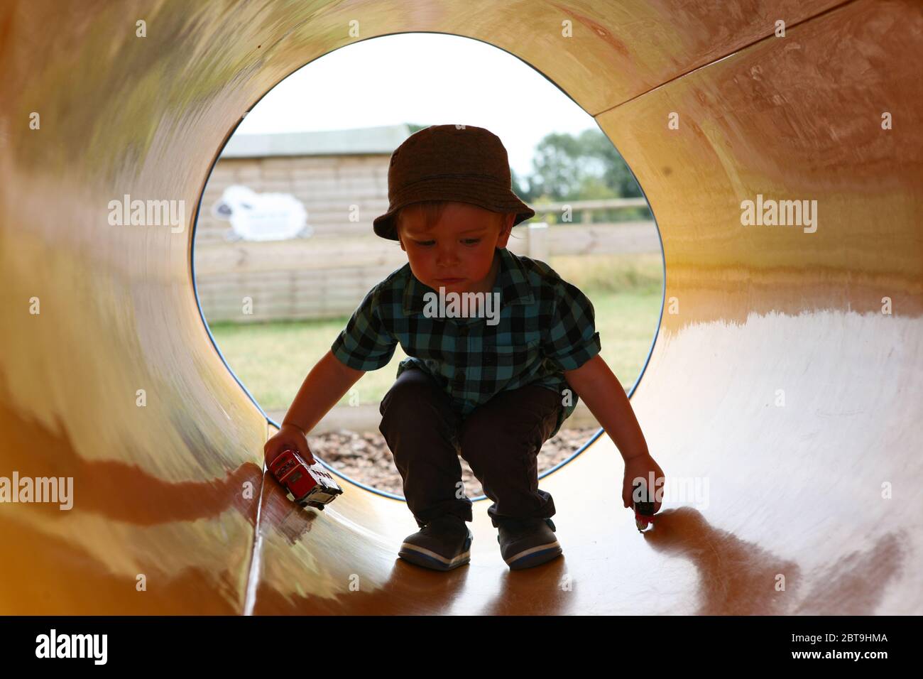 Adorable little boy, 1 - 2 years old, playing in a pipe, Manor Farm Country Park, Hampshire, England, UK.  MODEL RELEASED Stock Photo