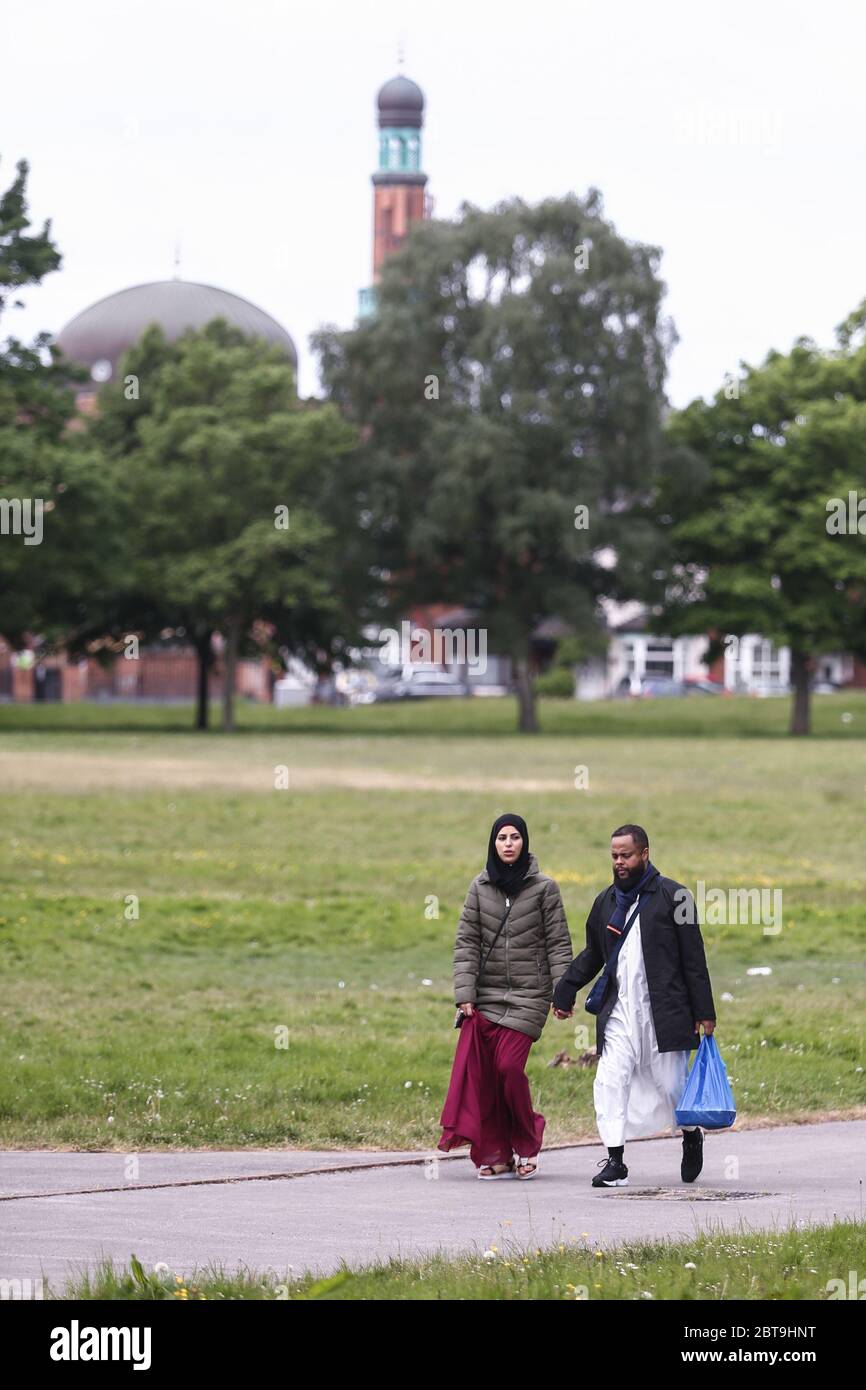 A young moslem or muslim married couple walk in the park, Small Heath, Birmingham UK with a mosque in the background Stock Photo