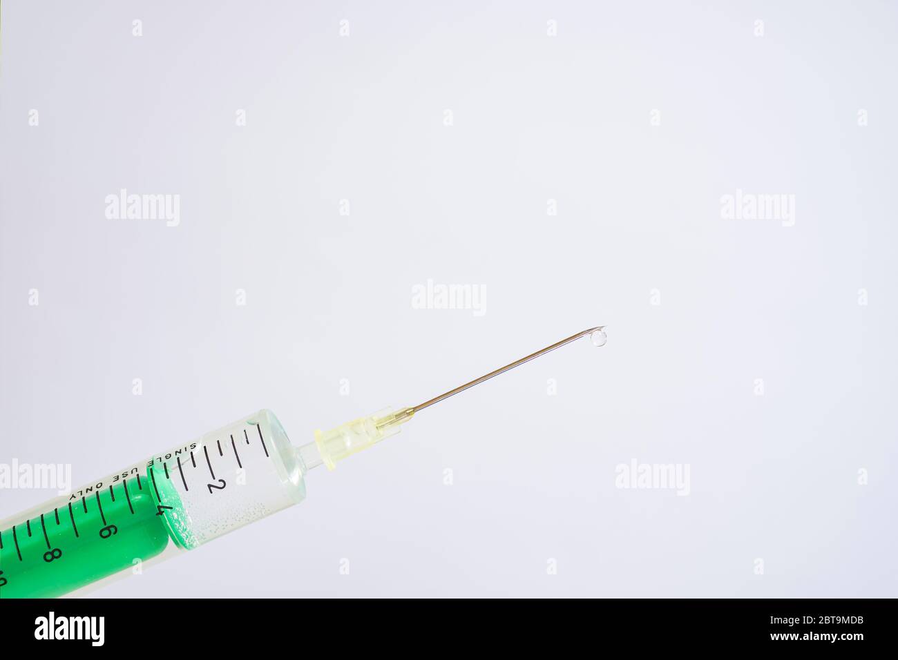 This photo illustration shows a disposable syringe with hypodermic needle, a white board behind Stock Photo