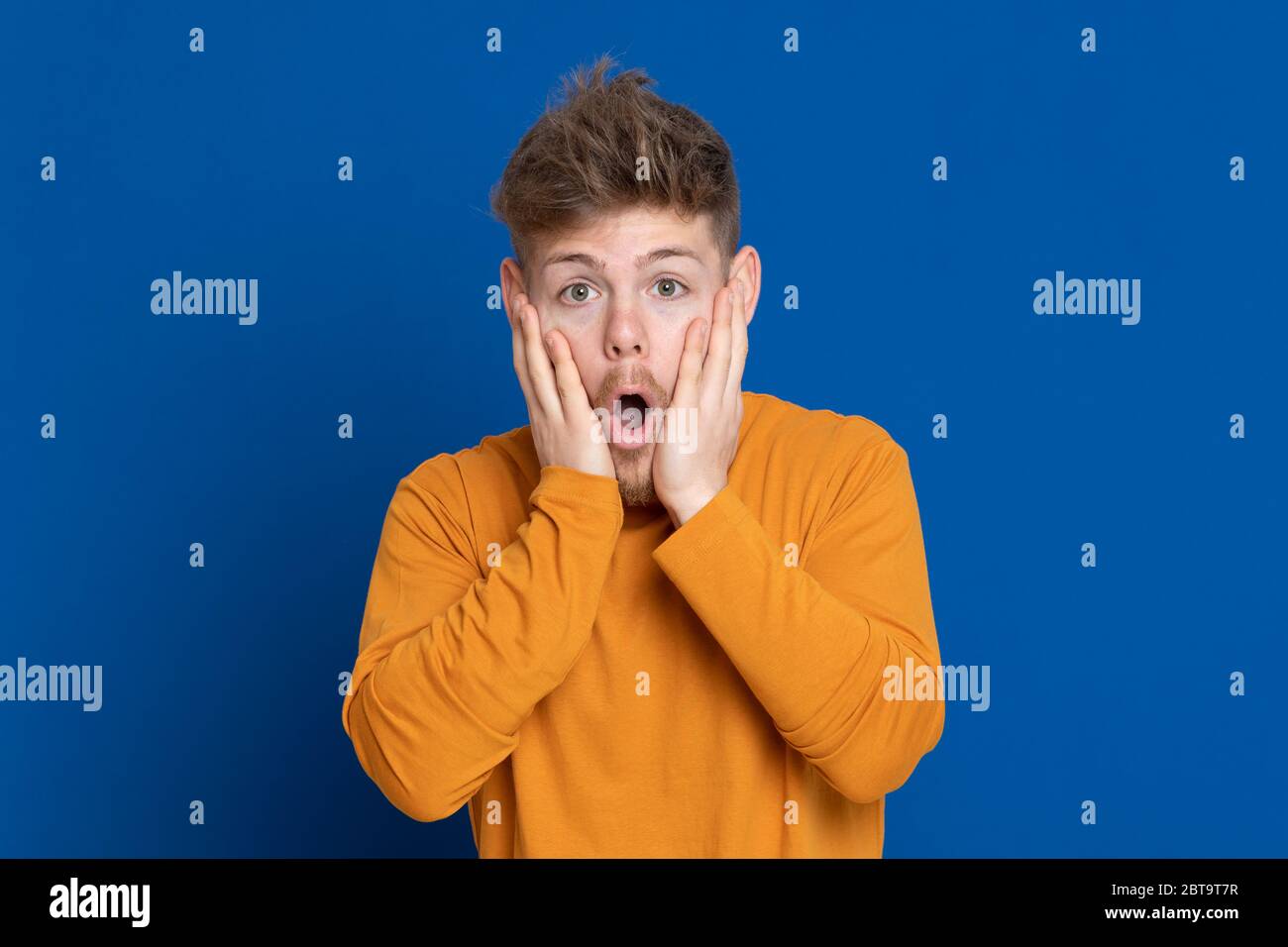 Attractive young guy with a yellow T-shirt on a blue background Stock ...