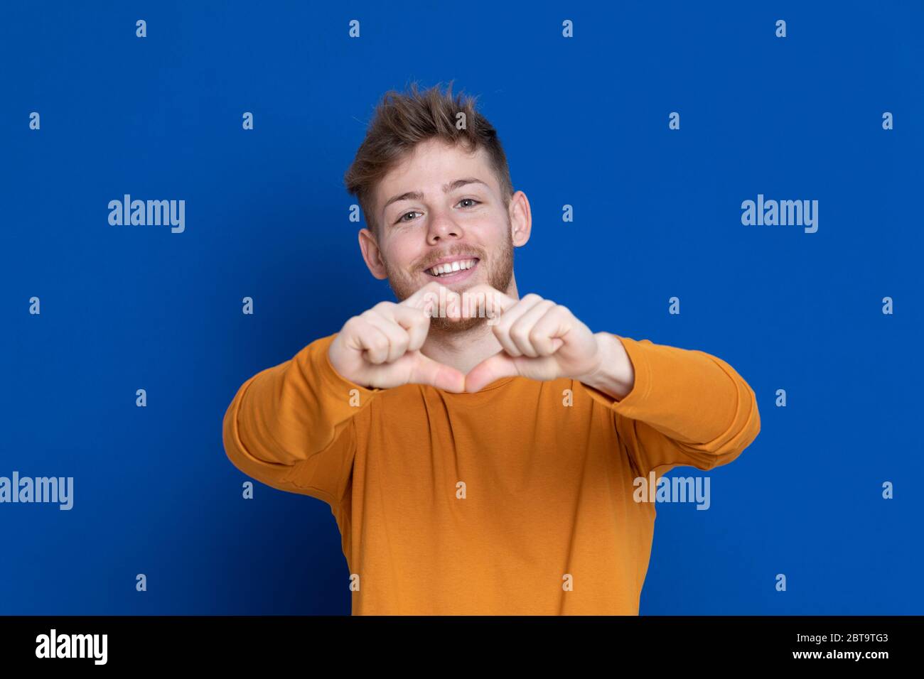 Attractive young guy with a yellow T-shirt on a blue background Stock ...