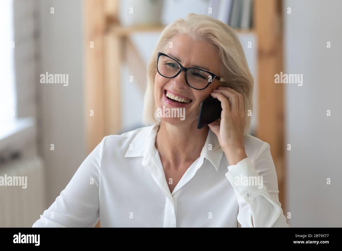 Smiling middle-aged woman have pleasant cell call Stock Photo