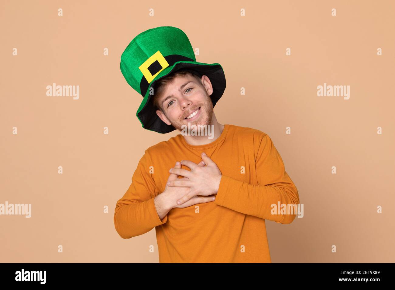 Attractive young guy with a big green hat on a yellow background Stock ...