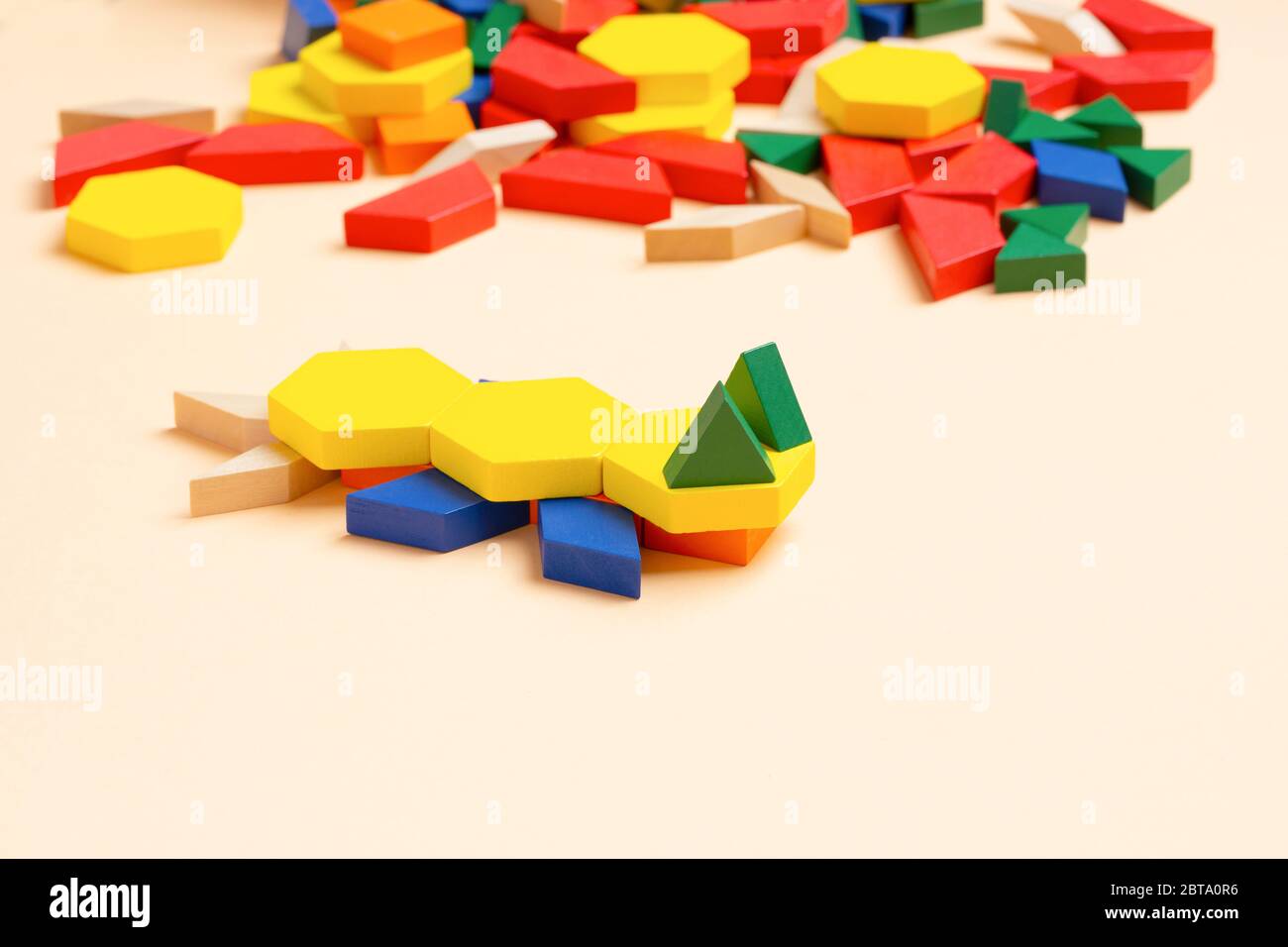 lizard animal. A child plays with colored blocks constructs a model on a light background. Stock Photo