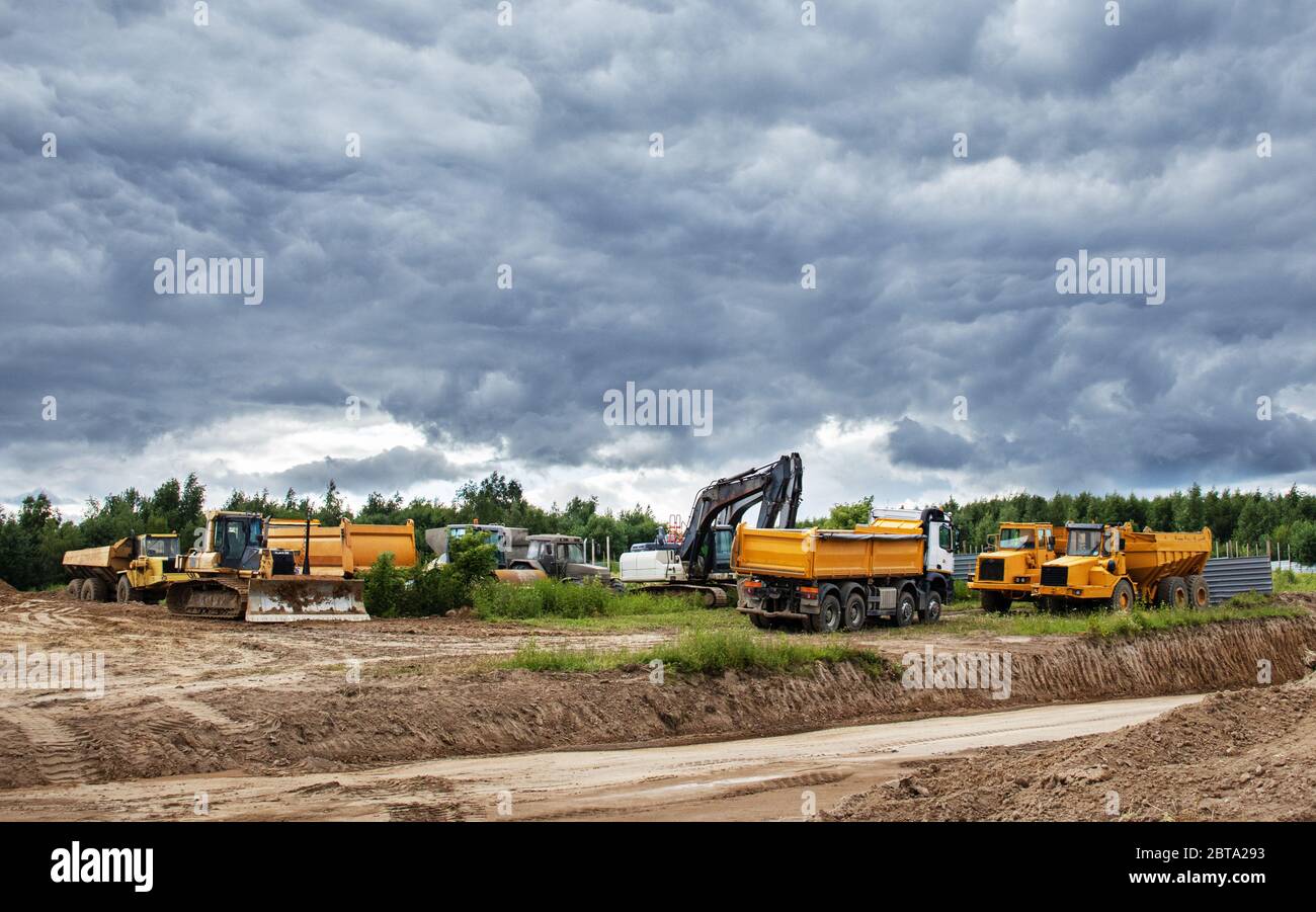 construction site with excavators, dump, truck, tree, cloudy sky on a ...