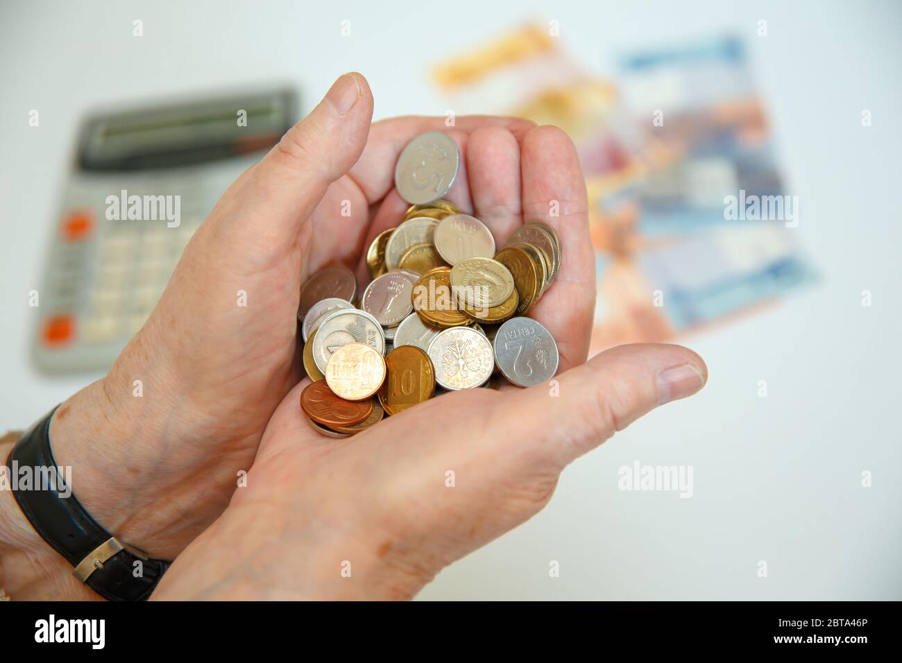 An elderly woman holds many different coins in her hands. Financial concept Stock Photo