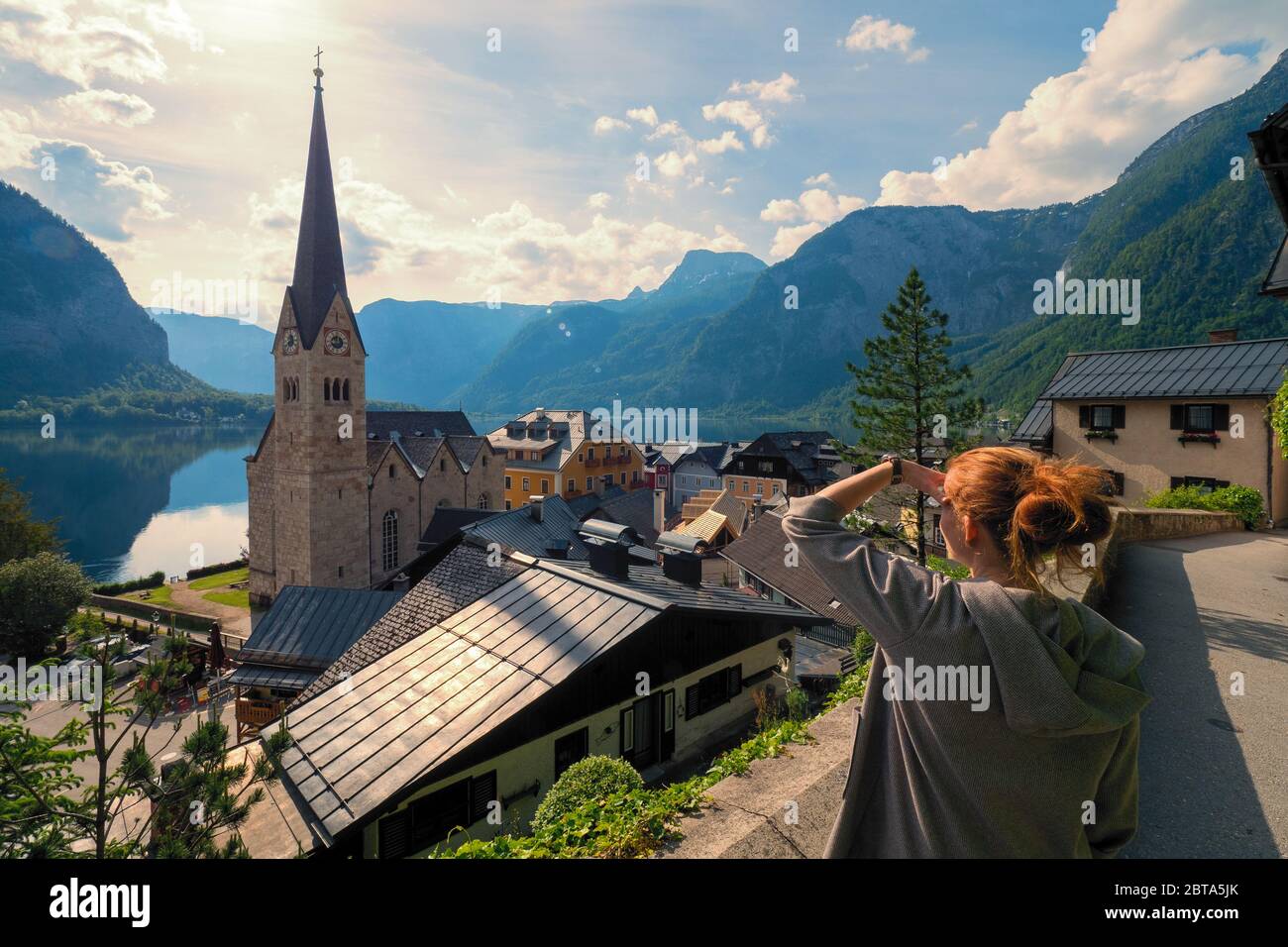 Female tourist looking at stunning Hallstatt, Salzkammergut region, OÖ, Austria, from an elevated viewing point above the roofs of the famous village Stock Photo