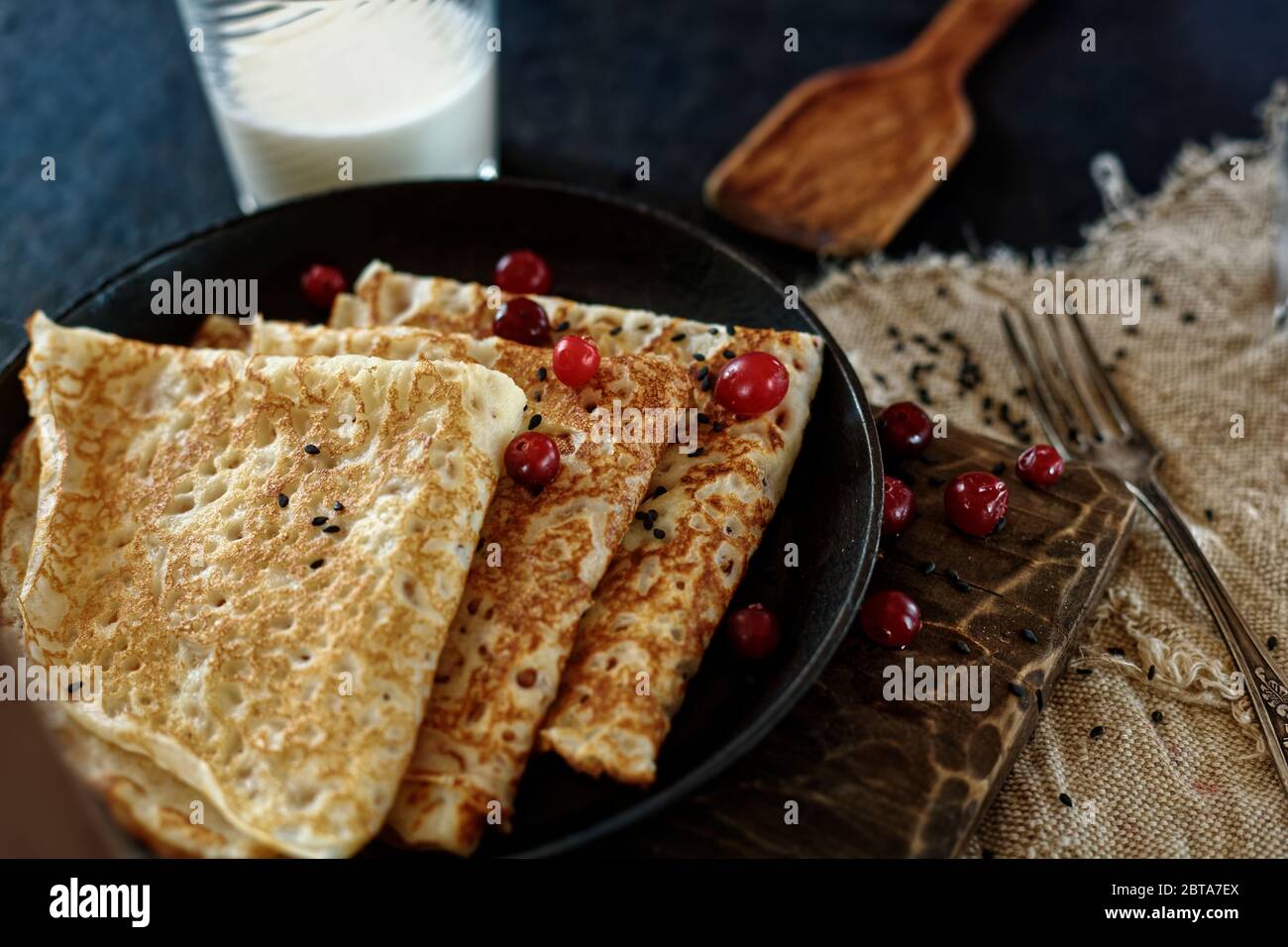 Delicious home-cooked food. Pancakes in a frying pan with cranberry berries and milk. Rustic style Stock Photo