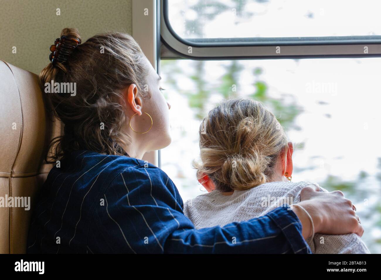 Two girls look out of the window at the scenery on the train  to Ella from Nanu Oya. Stock Photo