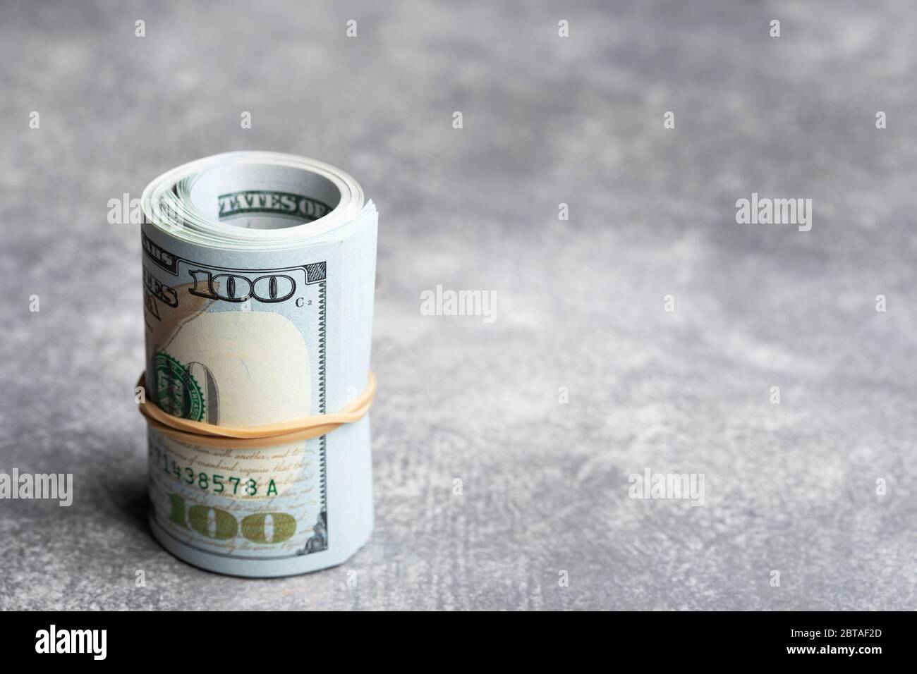 Roll of money in rubber on stone background. Stock Photo