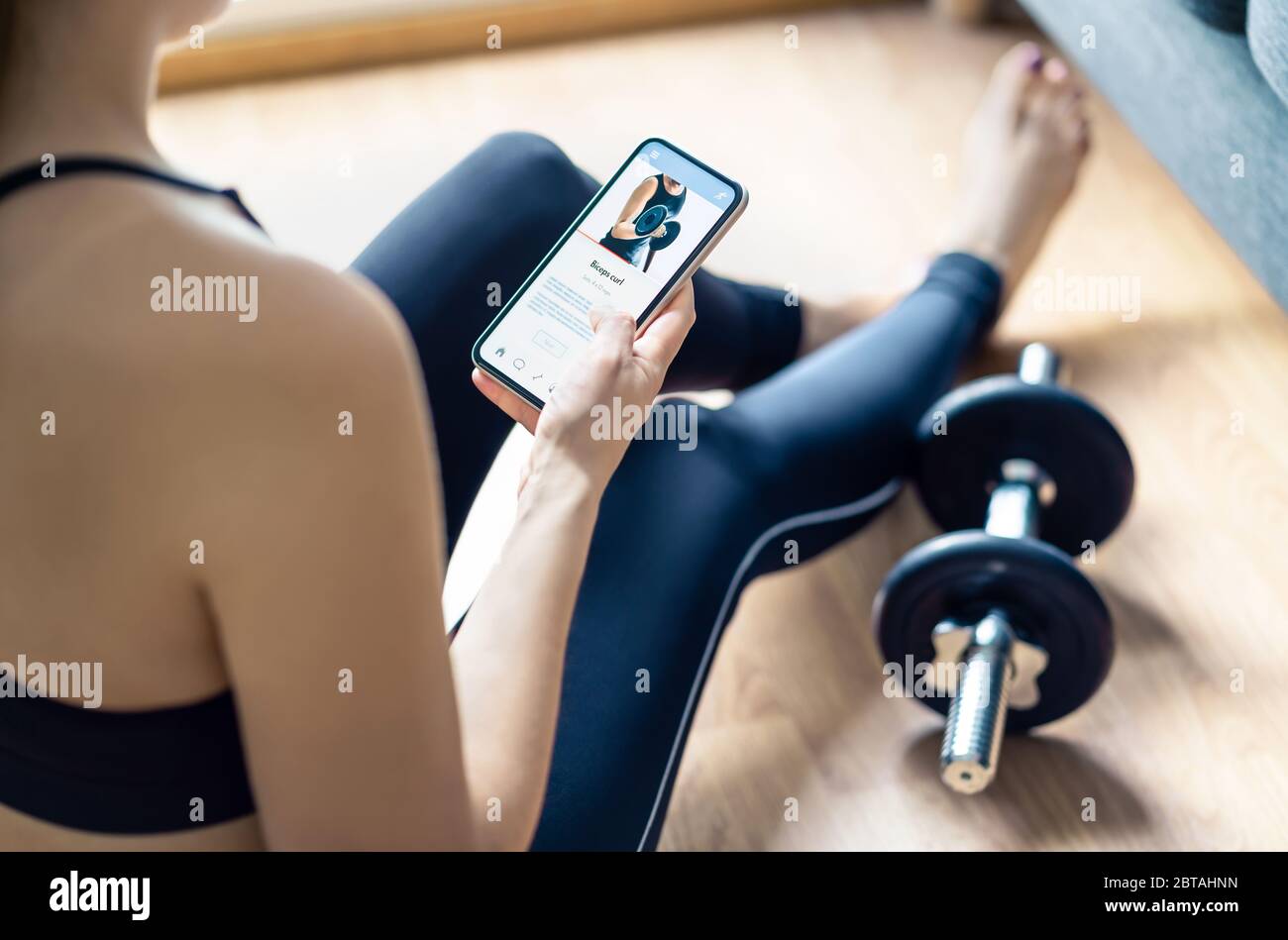 Home gym workout with online exercise app in phone. Fit woman watching training tutorial video or using digital personal trainer with smartphone. Stock Photo