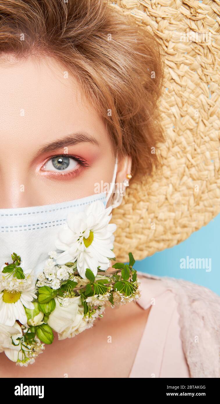 Face mask design with flowers. Portrait of beautiful woman with blue eyes, straw hat and mask Stock Photo