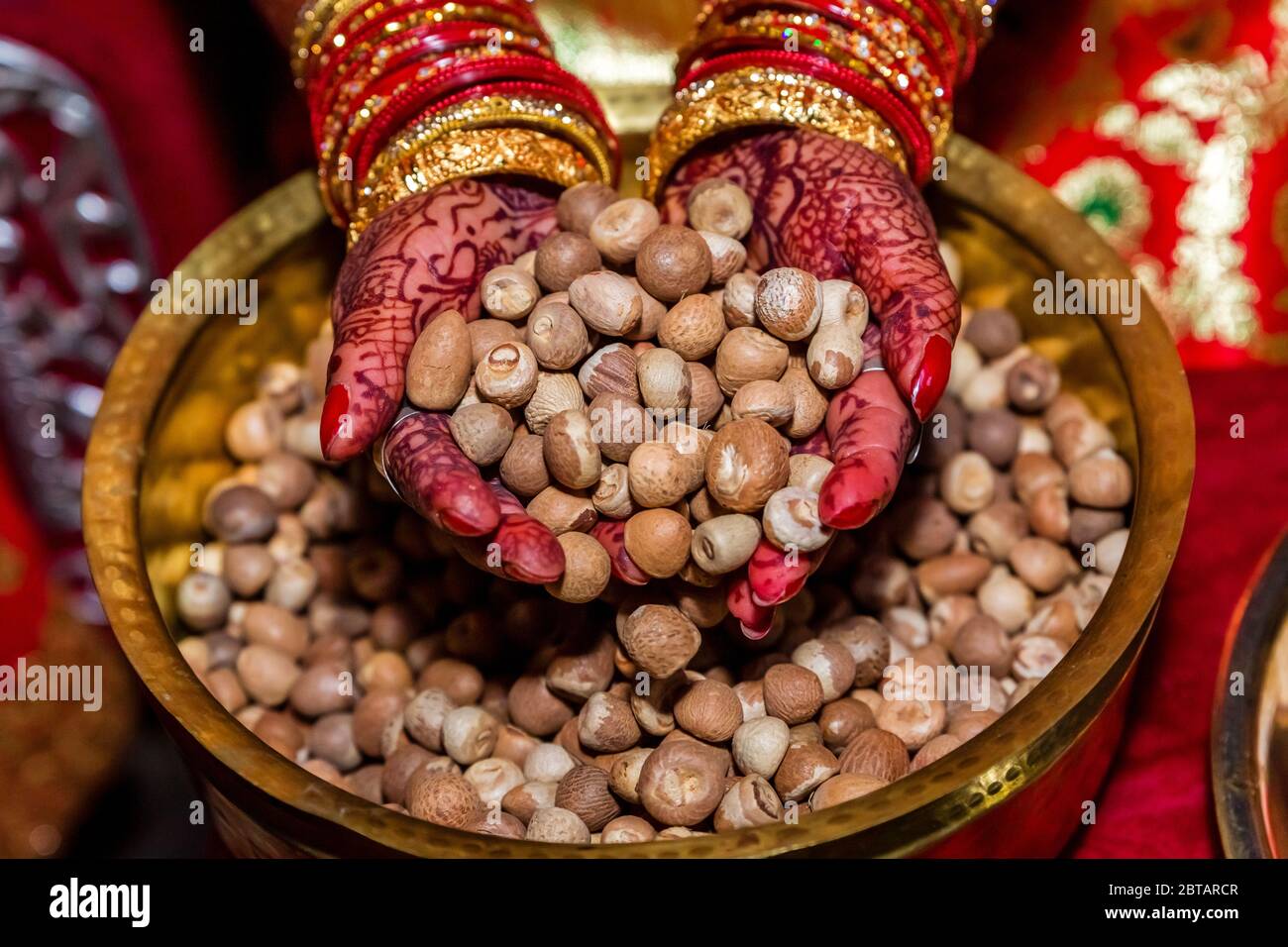 Bride hands with Colorful Mehendi holding a handful Betel Nuts,Betel Nuts Background.Supari Stock Photo