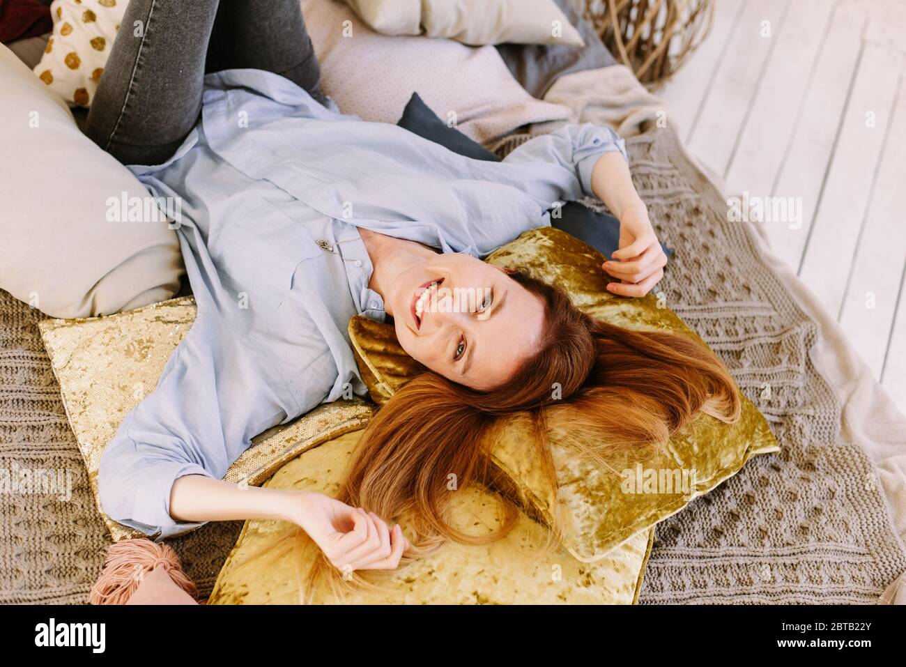 Lovely young woman is lying at home in a bright bed and smiling. Photo ...
