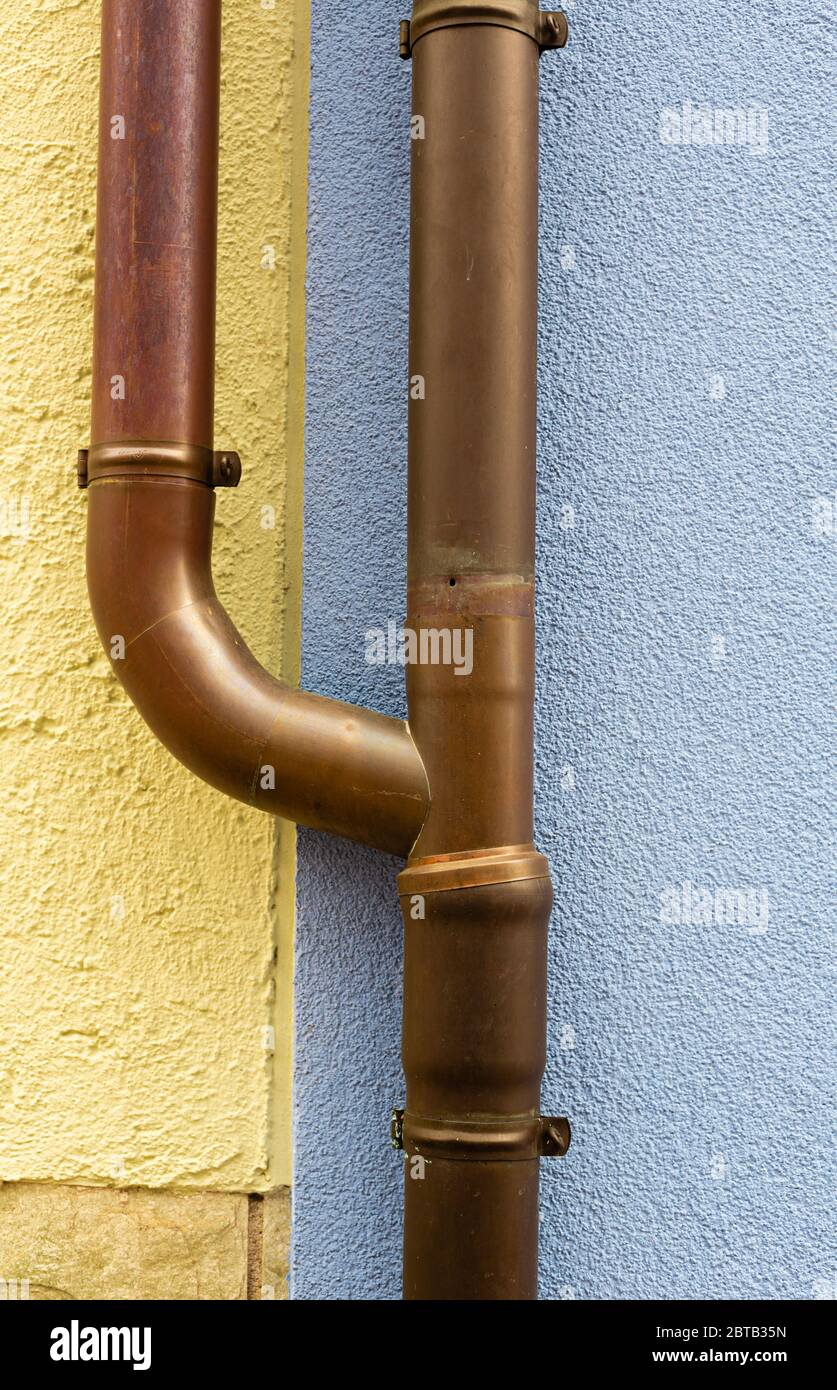 Rainwater drainage pipe. Sewage system. Pipes on the facade of the building. House after renovation. Metal constructions. Rough surfaces. Stock Photo