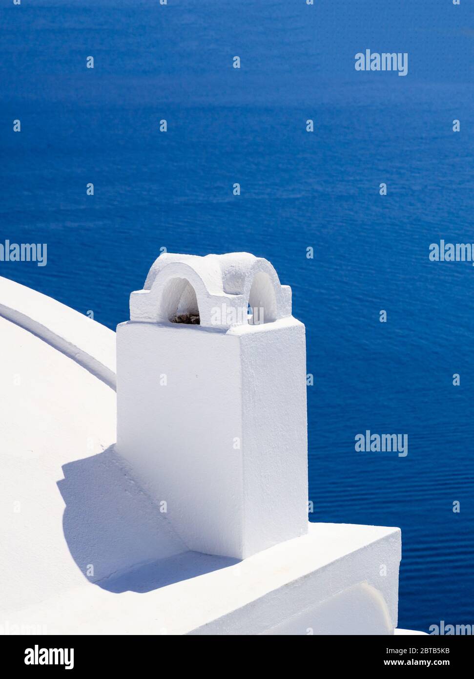 Santorini island, Greece, White painted chimney closeup view on caldera overlooking the sea. Traditional architecture against blue sea background, ver Stock Photo