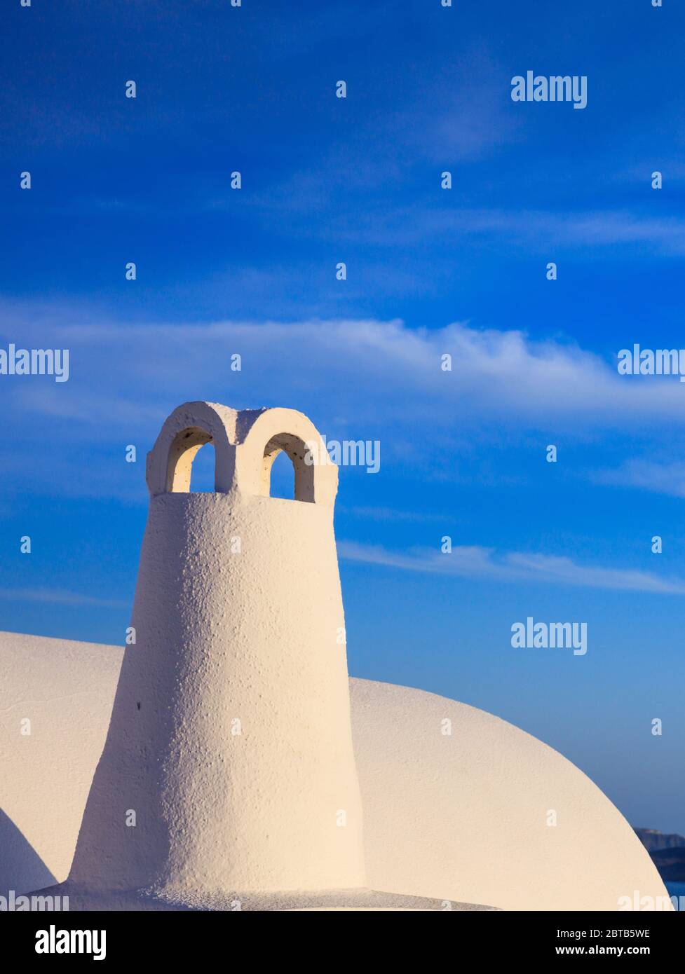 Santorini island, Greece, White painted chimney closeup view on caldera.Traditional architectural detail against blue sky background, vertical photo Stock Photo