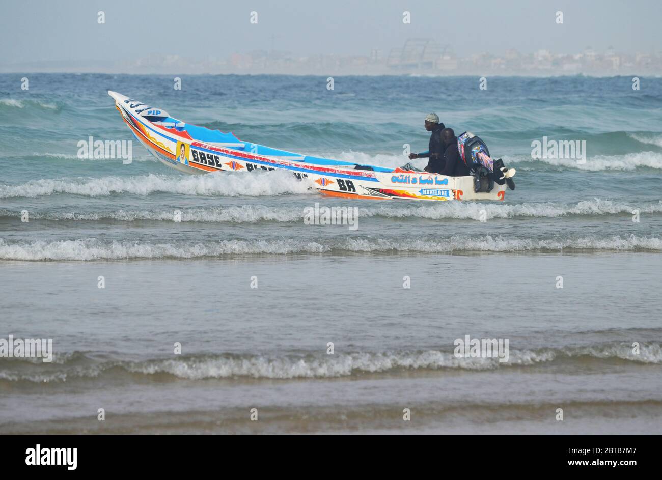 A pirogue (artisanal fishing boat) braving the surf at Yoff beach, Dakar, Senegal Stock Photo