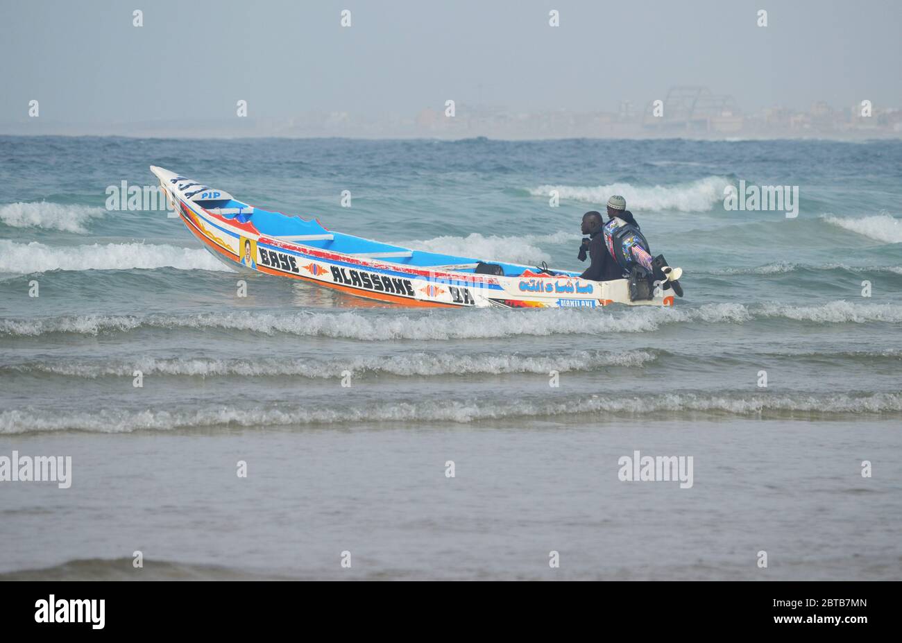 A pirogue (artisanal fishing boat) braving the surf at Yoff beach, Dakar, Senegal Stock Photo