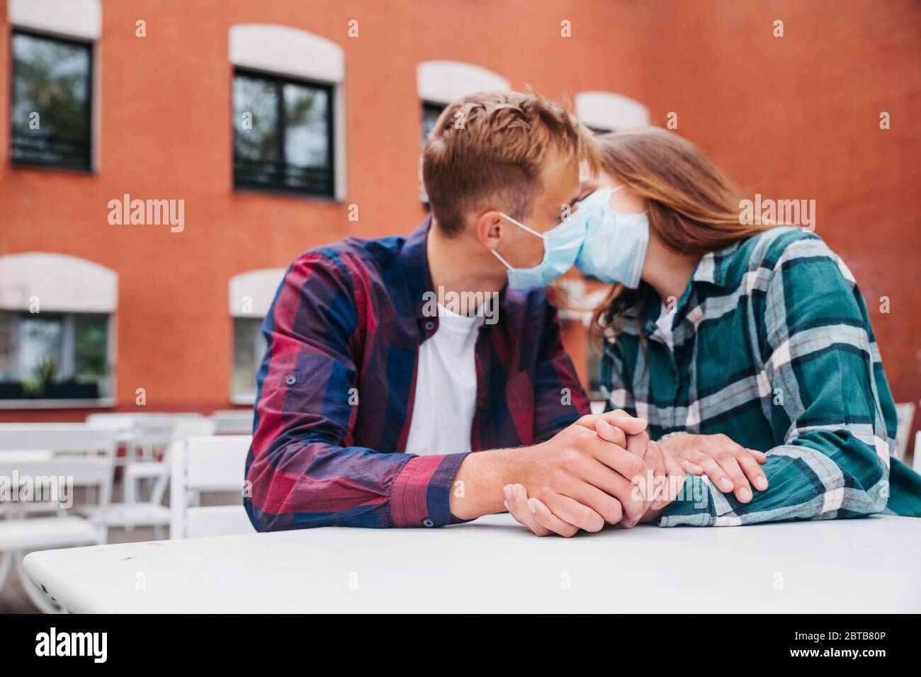 Couple in love, man and woman kissing each other in protective medical mask on face Stock Photo