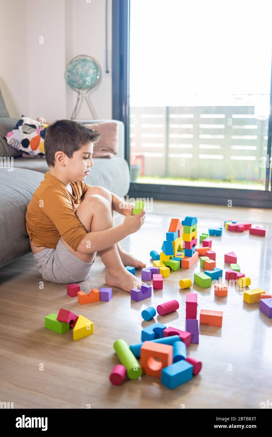 Bored child playing with blocks at home Stock Photo
