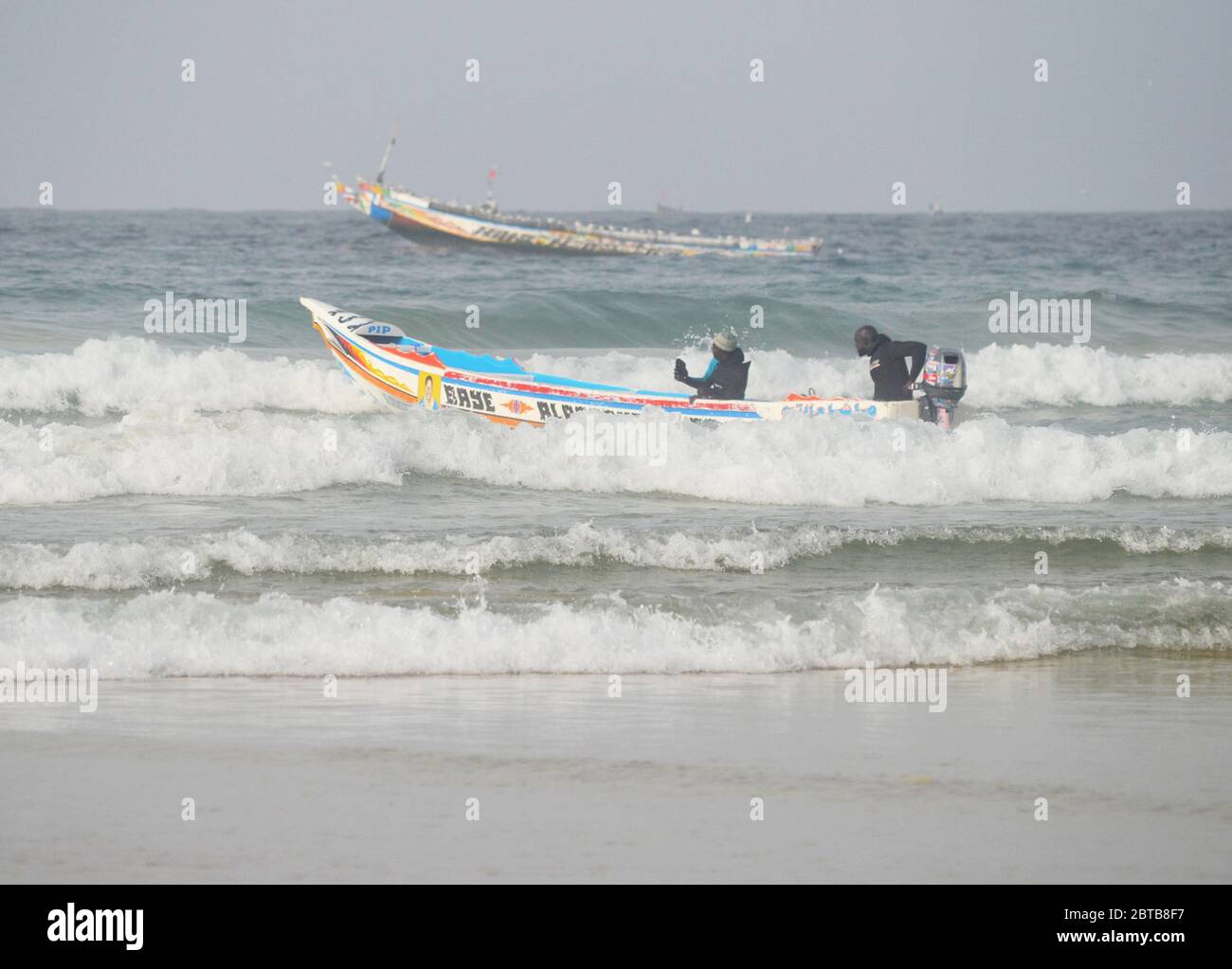 A pirogue (artisanal fishing boat) braving the surf at Yoff beach, Dakar, Senegal Stock Photo