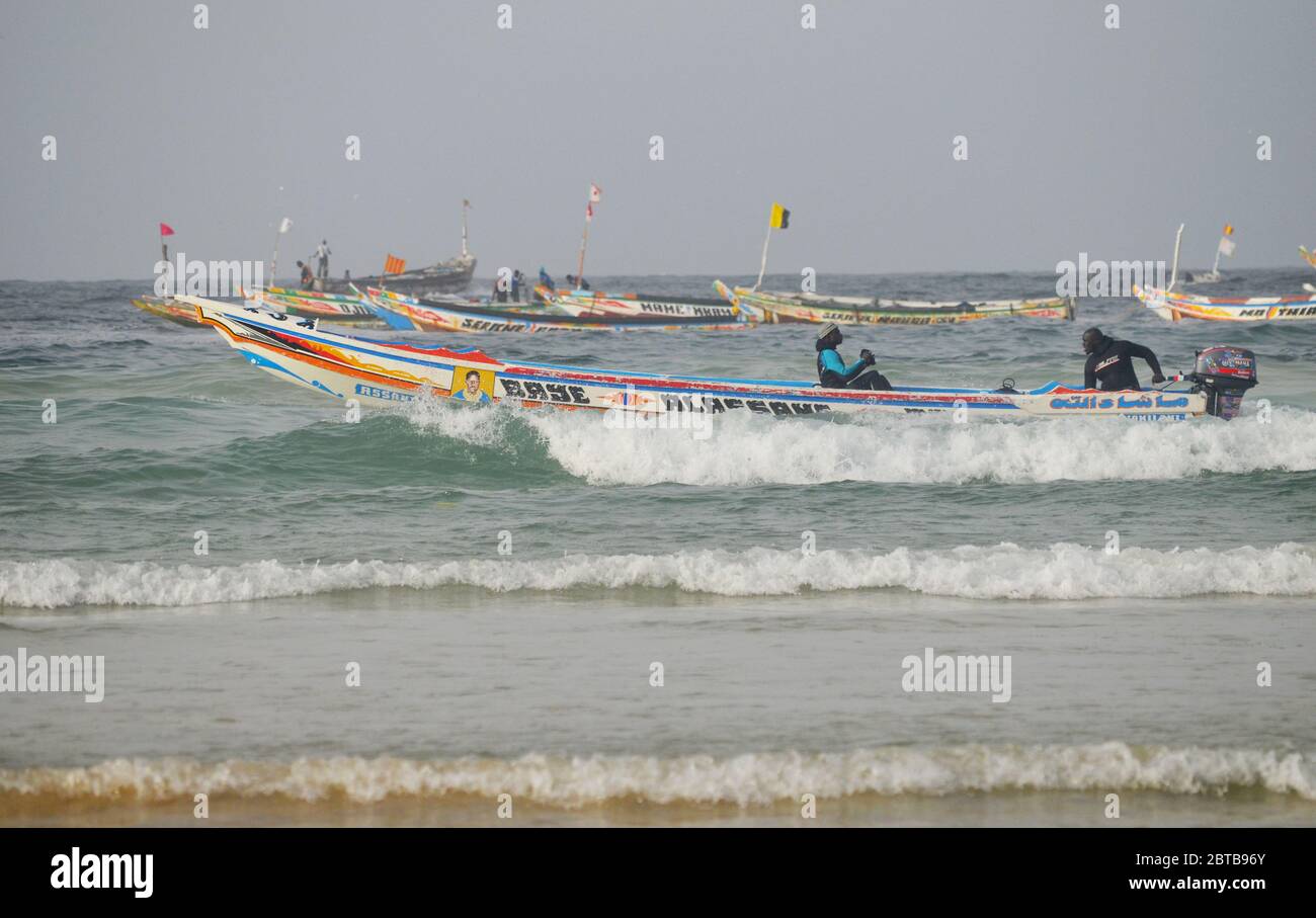 A pirogue (artisanal fishing boat) braving the surf at Yoff beach, Dakar, Senegal Stock Photo