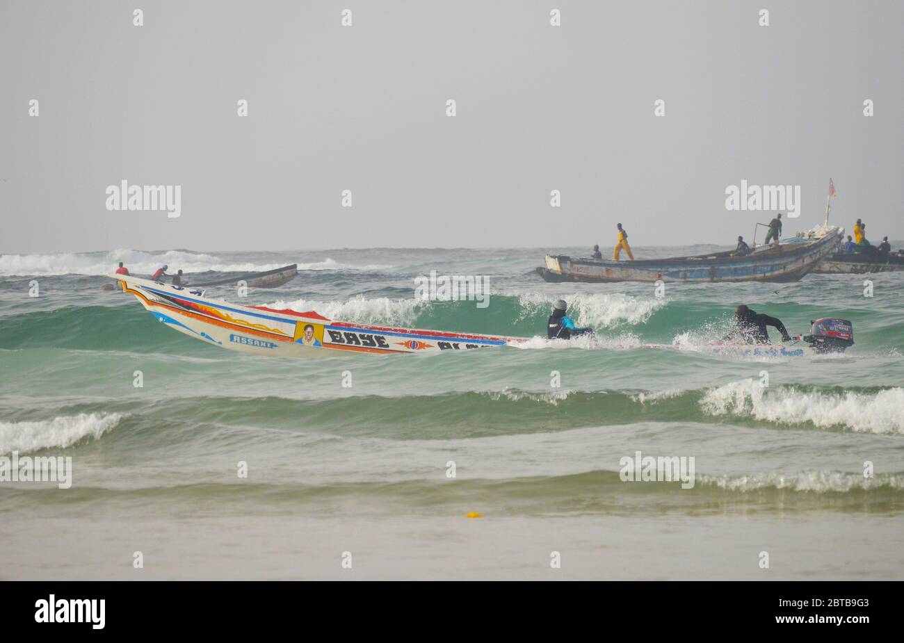 A pirogue (artisanal fishing boat) braving the surf at Yoff beach, Dakar, Senegal Stock Photo