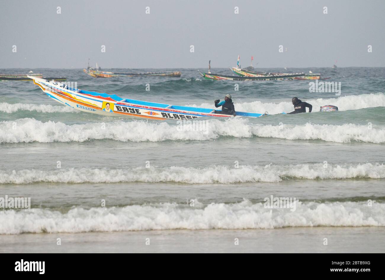 A pirogue (artisanal fishing boat) braving the surf at Yoff beach, Dakar, Senegal Stock Photo